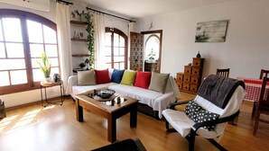 A living room with a sofa, armchair, coffee table, and a wooden cabinet. - Holiday Home 'Monte Azul' with Private Pool, Wi-Fi and Air Conditioning (Benajarafe)