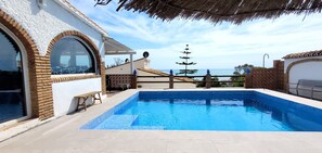 A swimming pool with a view of the sea, a covered patio, and a building with a tiled roof. - Holiday Home 'Monte Azul' with Private Pool, Wi-Fi and Air Conditioning (Benajarafe)