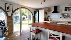 A kitchen with a wooden countertop, white chairs, and a dining table. - Holiday Home 'Monte Azul' with Private Pool, Wi-Fi and Air Conditioning (Benajarafe)