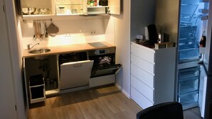 Eine kleine Küche mit Einbauofen, Spüle und Kühlschrank.