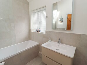 Ein Badezimmer mit Badewanne, Waschbecken und Fenster mit Jalousien.