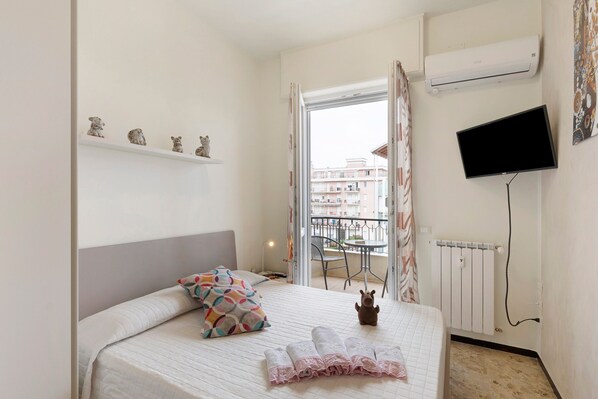 A bedroom with a bed, a TV, a radiator, and a balcony view. - Apartment 'Alloggio Gallinara' with Sea View, Wi-Fi, and Air Conditioning (Albenga)