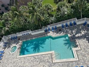 Luftaufnahme eines Swimmingpools, umgeben von Liegestühlen und Palmen.