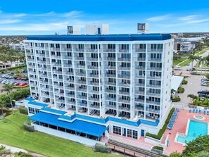 Een hotel met meerdere verdiepingen, balkons, een zwembad en een overdekt buitengebied.