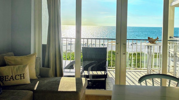 Een kamer met uitzicht op het strand, een balkon met een stoel en een tafel.