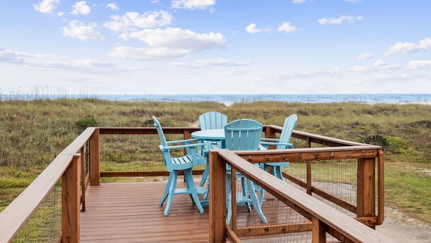 A wooden deck with blue chairs and a table overlooking a beach. - Amelia Island Beach Bungalow Directly on the Beach - Upstairs unit (Fernandina Beach)