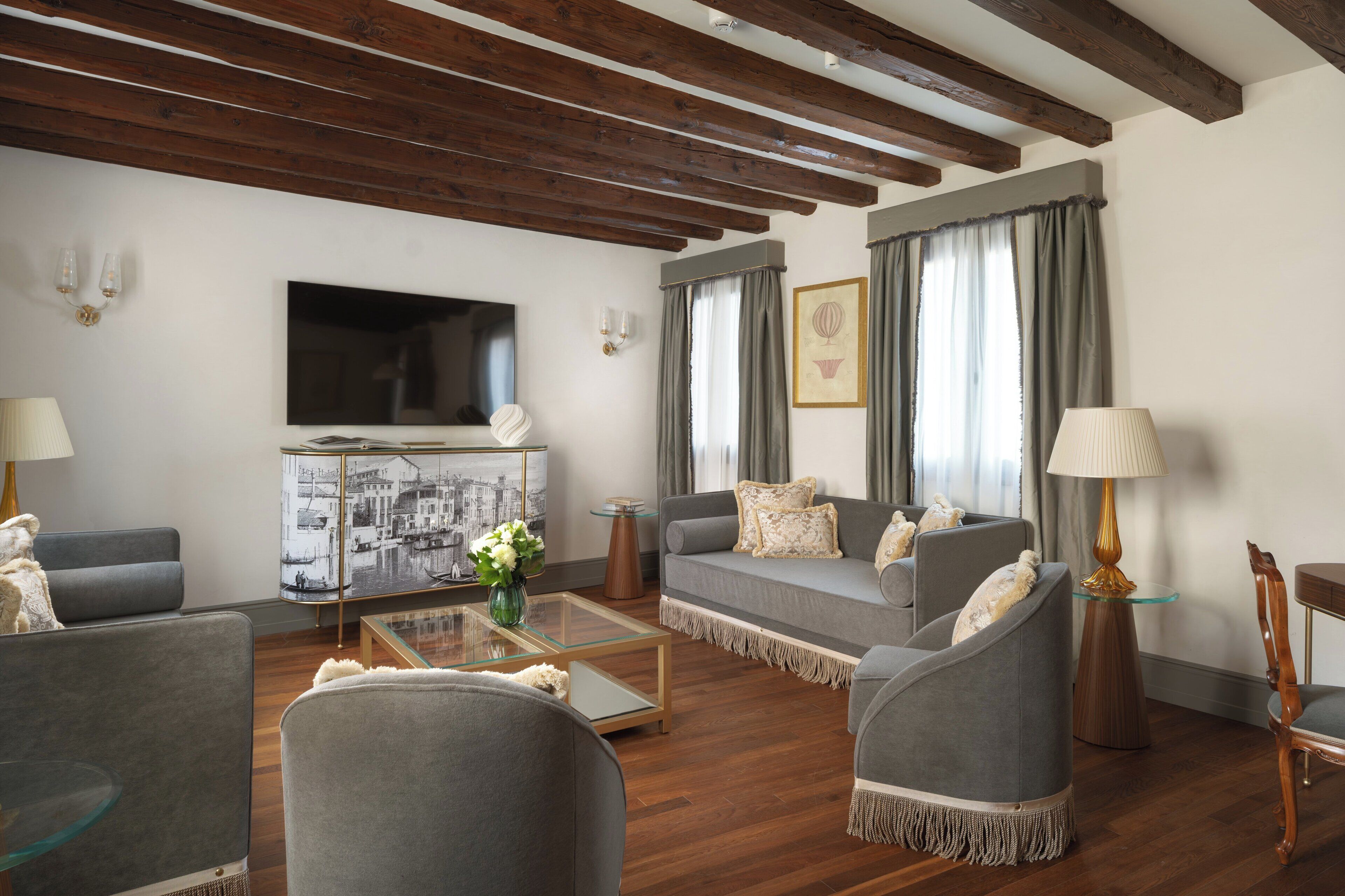 Una sala de estar moderna con un sofá, sillones, una mesa de centro y un televisor de pantalla plana.