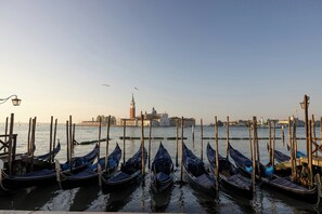 Gondolas docked at a waterfront, with a historic building and a tower in the background. - Gabrielli Luxury Apartments Venezia - Starhotels Collezione (Venice)