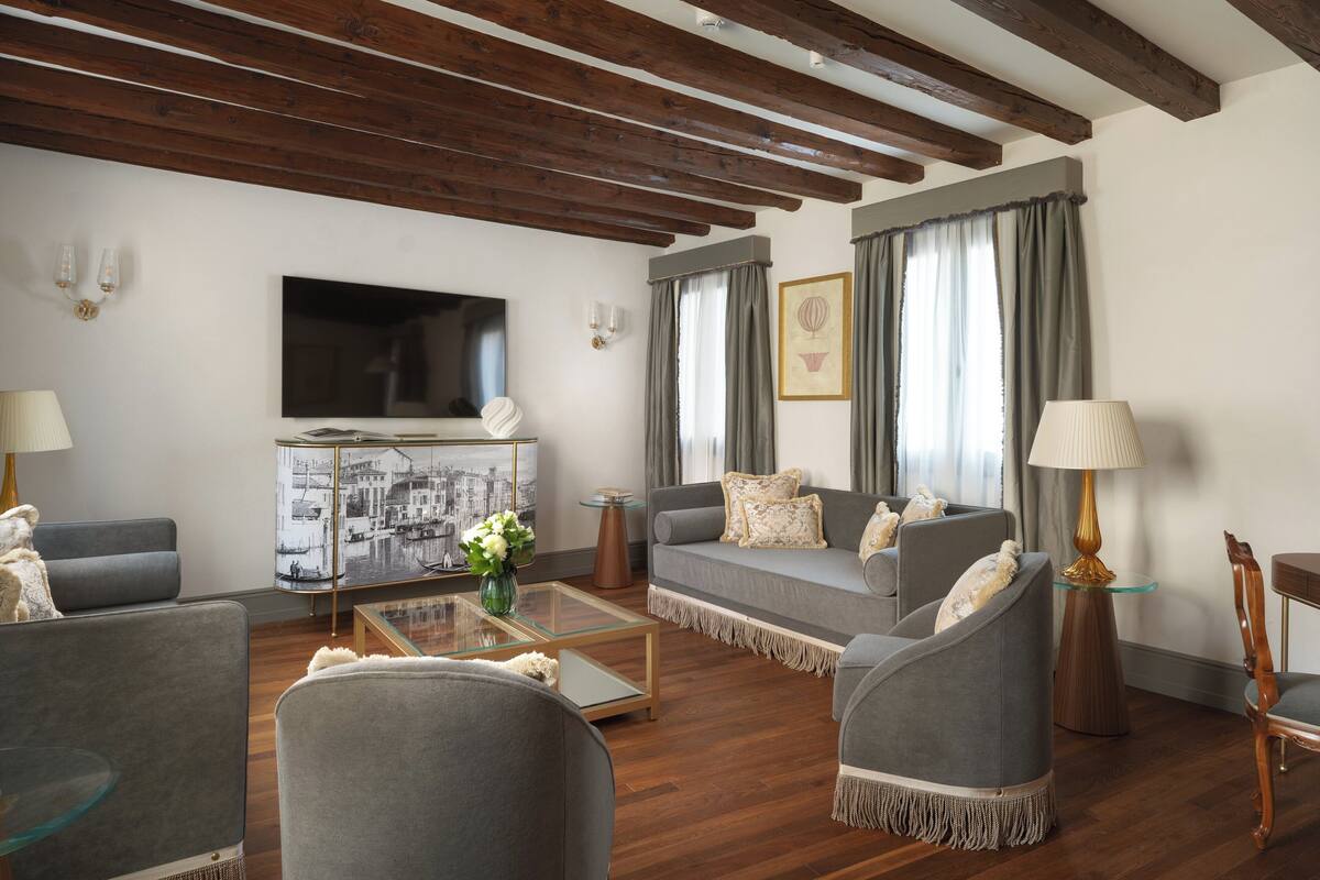 Una sala de estar moderna con un sofá, sillones, una mesa de centro y un televisor de pantalla plana.