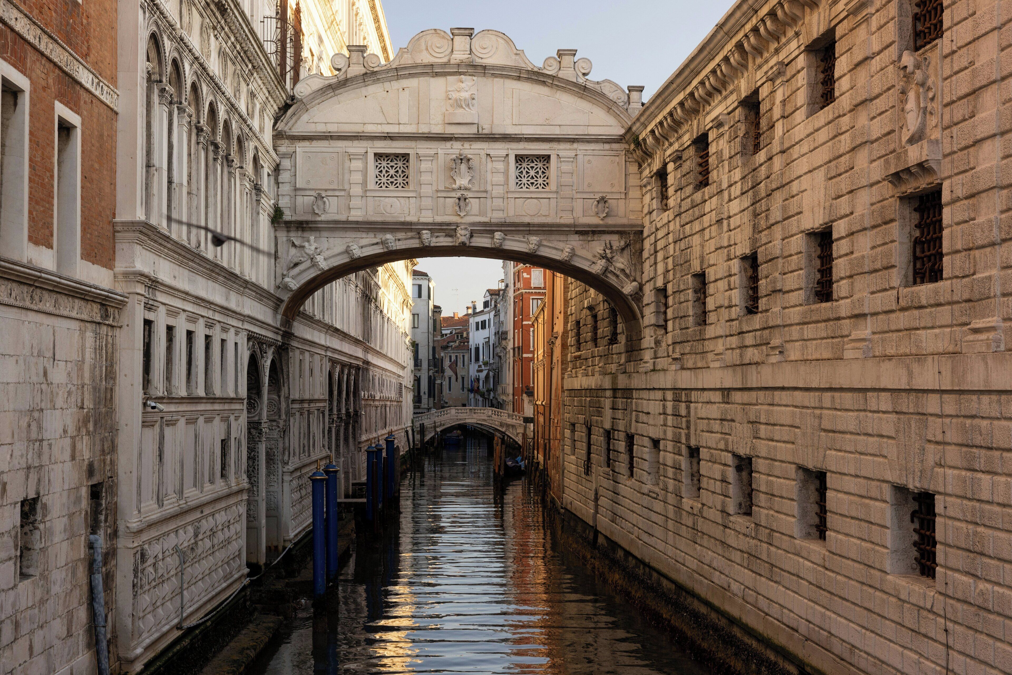 A narrow canal with a stone bridge and buildings on either side.