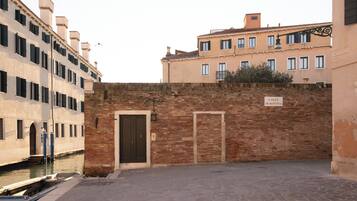 A narrow alley with a brick wall, a canal, and buildings with balconies.