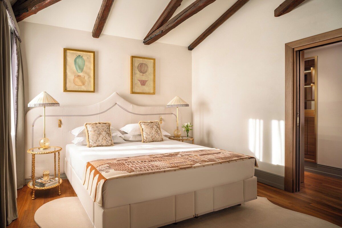 Quarto com uma cama grande, duas luminárias de cabeceira e uma obra de arte emoldurada na parede.