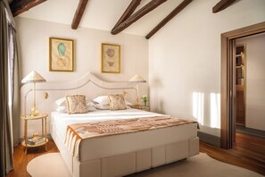 Une chambre à coucher avec un grand lit, deux lampes de chevet et une œuvre d’art encadrée au mur.