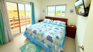 A bedroom with a bed, a TV, a window, and an air conditioning unit. - Charming 1-bedroom apartment in perfect Oranjestad with outside Pool (Oranjestad)