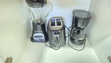 A kitchen counter with a blender, toaster, and coffee maker.