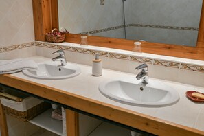 A bathroom with two sinks, a mirror, and a wooden vanity.