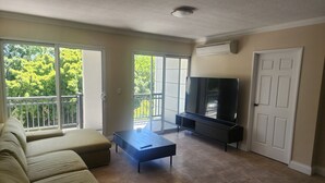 A living room with a sofa, a coffee table, a TV, and a sliding glass door leading to a balcony. - West Perth apartment. Walking distance to CBD, King's Park and Public transport. (West Perth)