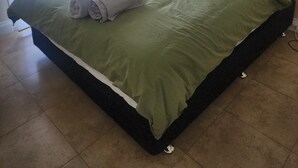 A neatly made bed with green bedding and white pillows, a window with a view of greenery, and a tiled floor. - West Perth apartment. Walking distance to CBD, King's Park and Public transport. (West Perth)