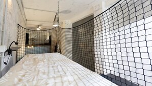 Ein Zimmer mit einem Bett, einer Hängelampe und einem Insektenschutznetz.