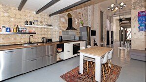 Eine moderne Küche mit Kochinsel, Edelstahlgeräten und einem Essbereich mit Holztisch und Stühlen.