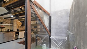 Eine moderne Küche mit Edelstahlgeräten, einer Holztreppe und einer kleinen Sitzecke mit grünem Teppich.