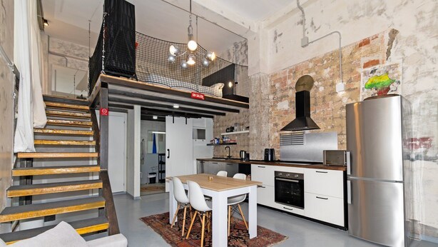 Eine moderne Küche mit Essbereich, einer Treppe und einem Wohnzimmer mit Sofa.