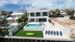 A modern multi-story building with a rooftop pool and outdoor seating area. -     Luxury Canalfront Villa | 3BR | Private Pool/Hot Tub | 5 Min to Grace Bay (Leeward)