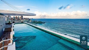 A swimming pool with a view of the ocean and a city skyline. - Enjoy your stay steps from Farol da Barra (Salvador)