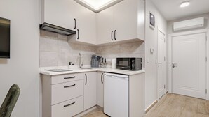 A modern kitchen with white cabinets, a dishwasher, a microwave, and a built-in oven. - Central Brand New Studio w/Balcony Near Metro (İstanbul)