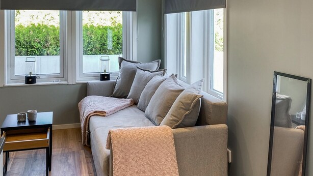 Ein gemütliches Zimmer mit einer Couch, einem kleinen Tisch und einem Fenster mit Blick auf Grünflächen.