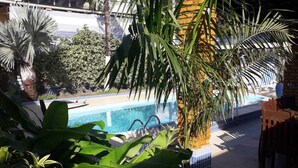 A pool area with a tiled border, surrounded by various plants and a brick wall. - Beach house in Porto de Galinhas with private pool. (Ipojuca)