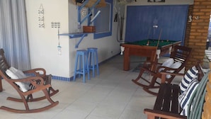 A room with a pool table, wooden rocking chairs, and a blue bar stool. - Beach house in Porto de Galinhas with private pool. (Ipojuca)