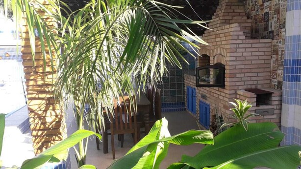 A courtyard with a brick wall, a tiled wall, and a hanging plant. - Beach house in Porto de Galinhas with private pool. (Ipojuca)