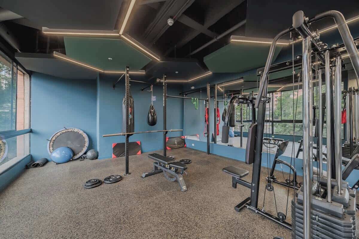 Un gimnasio con equipo de ejercicio, una jaula de sentadillas y una banca.