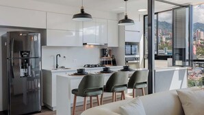 A modern kitchen with a stainless steel refrigerator, a central island with bar stools, and pendant lighting. - lEPl Nice Apt w/Pool, Good Zone, Bbq & Balcony (Medellín)