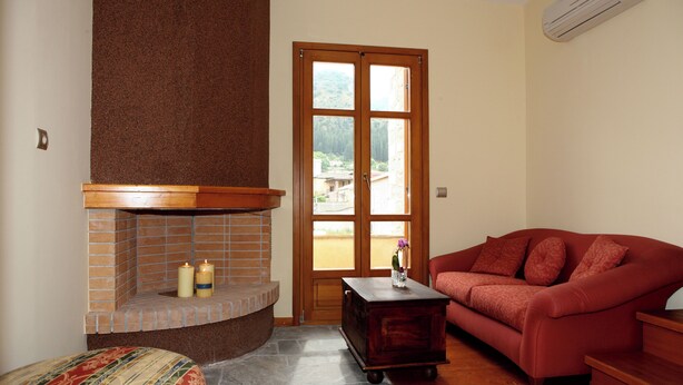 A living room with a fireplace, a sofa, a small table, and a door leading outside. - Despotato (Sparta)