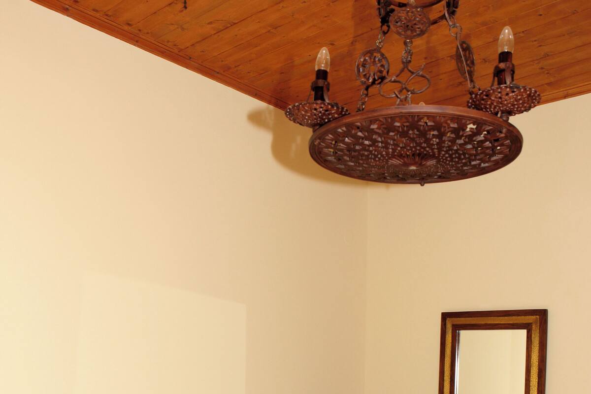 Un dormitorio con cabecera de madera, cómoda de madera, un espejo y una araña.