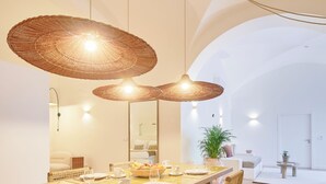 A dining area with a large wooden table, wicker chairs, and two large woven pendant lights. - Pátio do Tempo (Évora)