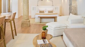 A spacious living area with a high arched ceiling, a central column, a sofa set, a coffee table with a plant, and a dining area with chairs and a table. - Pátio do Tempo (Évora)