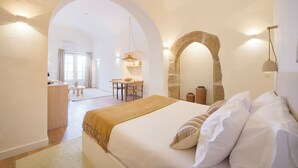 A bedroom with a large bed, a wooden desk, and a dining area. - Pátio do Tempo (Évora)