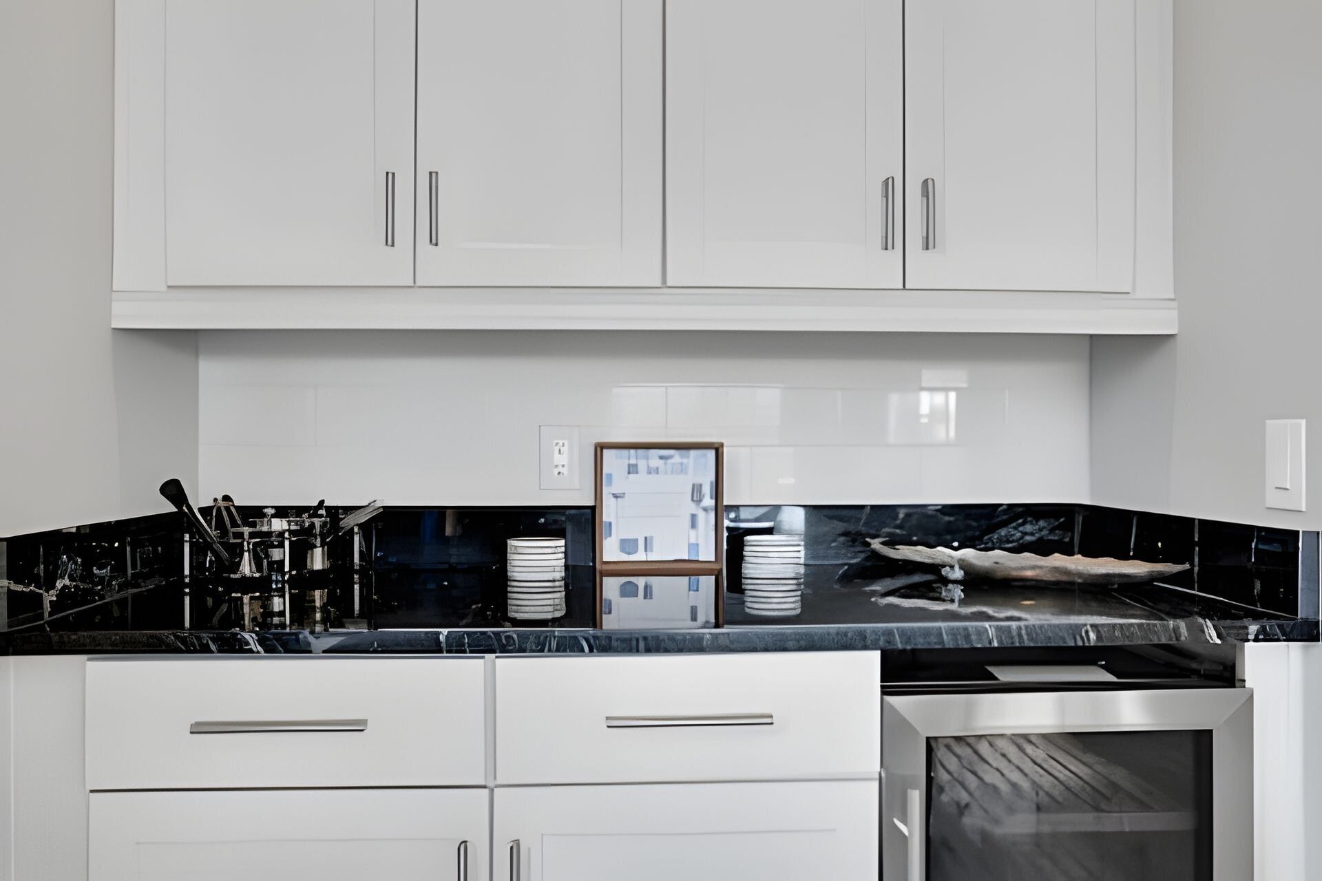 Una cucina moderna con mobili bianchi, un piano di lavoro nero ed elettrodomestici in acciaio inossidabile.