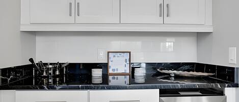 Una cucina moderna con mobili bianchi, un piano di lavoro nero ed elettrodomestici in acciaio inossidabile.