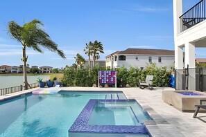 A swimming pool with a view of a lake, surrounded by greenery and buildings. - Reunion Luxury Villa w/ Lake View & Game Room (Kissimmee)