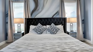 A bedroom with a large bed, two nightstands, a black upholstered headboard, and a wall with a wavy pattern. - Reunion Luxury Villa w/ Lake View & Game Room (Kissimmee)