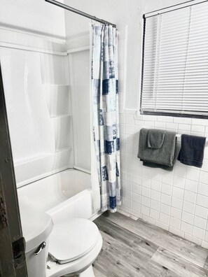 Une salle de bain avec douche, toilettes et un porte-serviettes avec deux serviettes.