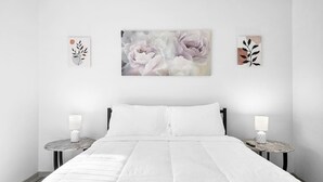 Un dormitorio con una cama grande, dos mesitas de noche y tres obras de arte colgadas en la pared.