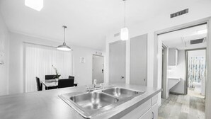 Una cocina moderna con una isla grande, electrodomésticos de acero inoxidable e iluminación colgante.