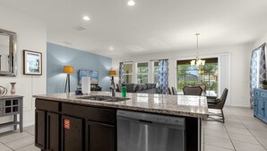 A modern kitchen with a granite countertop, stainless steel appliances, and a built-in dishwasher. - 5BR Villa w/ Pool + Resort Access – Solterra (Davenport)