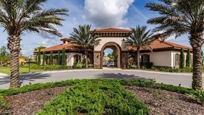 A building with a central archway, surrounded by palm trees and a landscaped garden. - 5BR Villa w/ Pool + Resort Access – Solterra (Davenport)
