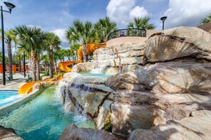 Een waterpark met een waterval, palmbomen en een zwembad.